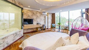 A modern hotel room with a large bed, a TV, a desk, and a view of the outdoors. - Ease Cloud Hotel (Beijing)