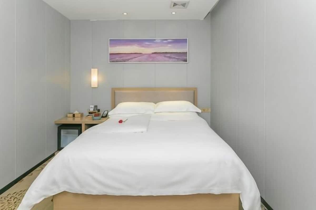 Une chambre d’hôtel avec un lit, une table de chevet, un tableau au mur et une lampe de chevet.