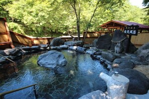 A traditional Japanese onsen with a wooden bathhouse in the background. - Metou Onsen Hotel (Ashoro)