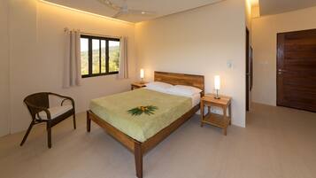 A bedroom with a wooden bed, a nightstand, a chair, a window with curtains, and a door.