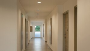 Un long couloir étroit, doté d’un sol carrelé et d’un éclairage encastré.
