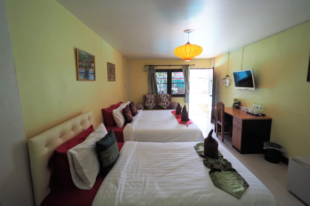 A hotel room with two beds, a desk, a TV, and a window with curtains.