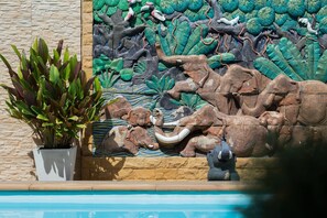 A decorative wall with animal carvings and a potted plant. - P.U. Inn Resort (Ayutthaya)