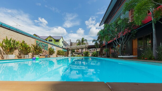 A swimming pool with a clear blue water surface, surrounded by a concrete deck and potted plants. - P.U. Inn Resort (Ayutthaya)