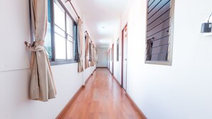 A long, narrow hallway with wooden flooring and large windows on one side. - P.U. Inn Resort (Ayutthaya)