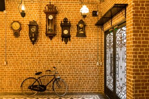 A brick wall with multiple clocks and a bicycle. - X9Hostel (Bangkok)