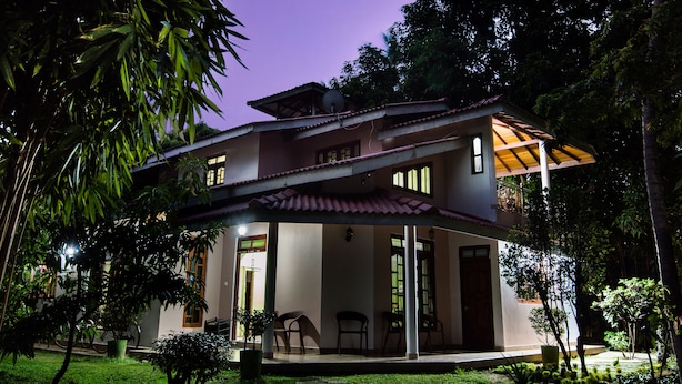 A two-story house with a covered porch, a satellite dish, and a garden with potted plants.