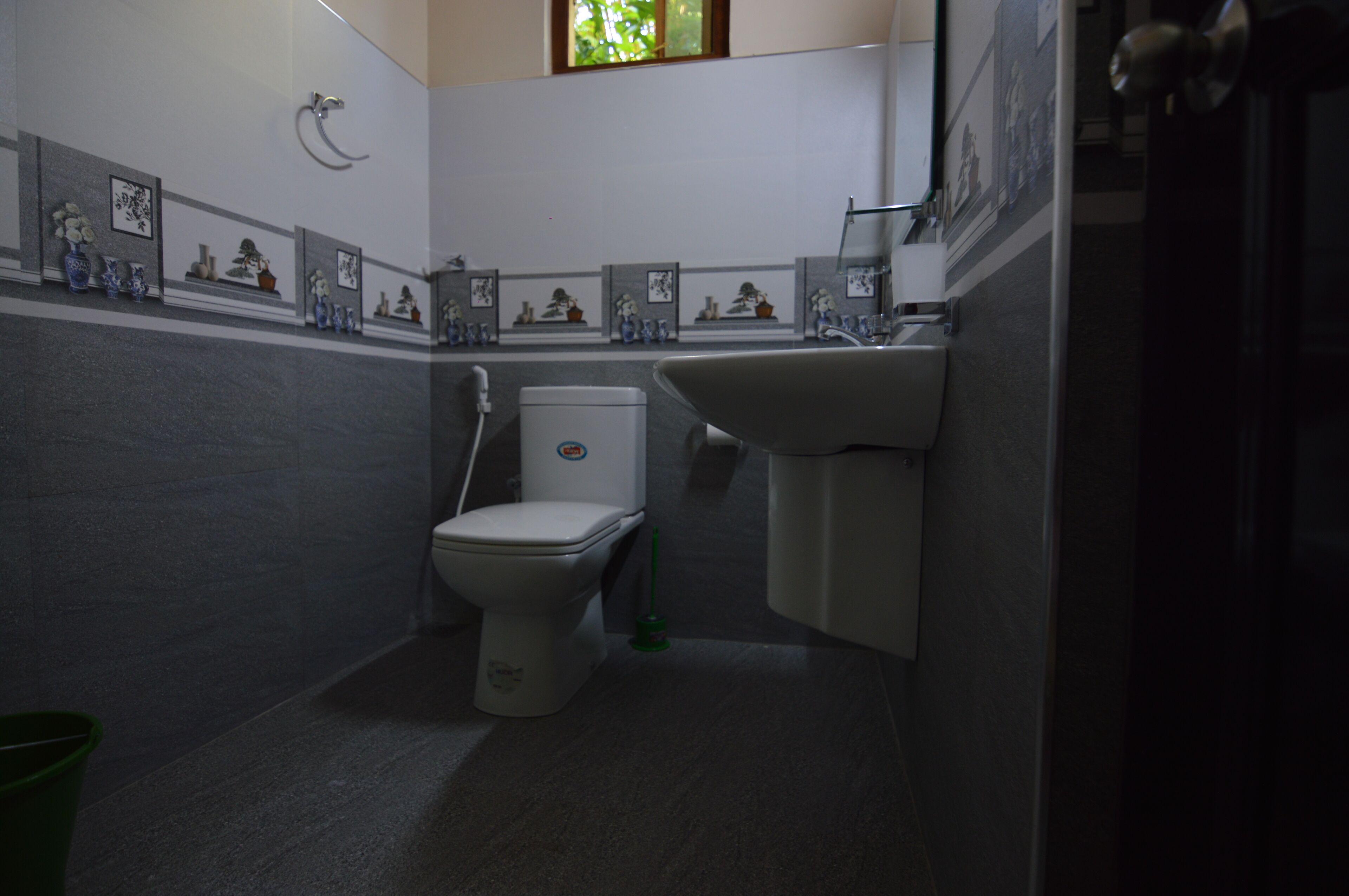 A compact bathroom with a toilet, sink, and a green bucket.