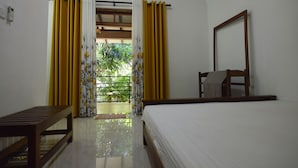 A bedroom with a bed, a wooden bench, a mirror, and yellow curtains.