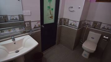 Een badkamer met een wastafel, toilet en een deur met een palmboommotief.