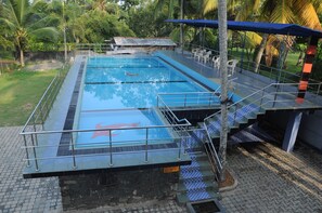 A swimming pool with a glass bottom, surrounded by a metal railing and steps leading down to the water. - Kamaro Holiday Resort (Bandaragama)