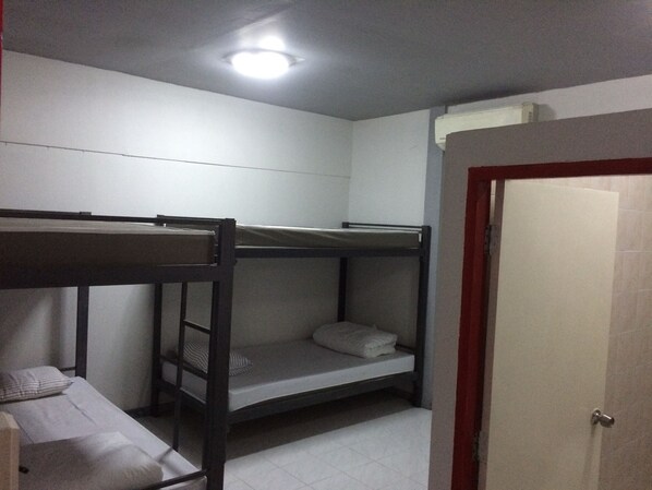 A bunk bed room with a door, white walls, and a ceiling light. - Il Treno Hostel (Ayutthaya)