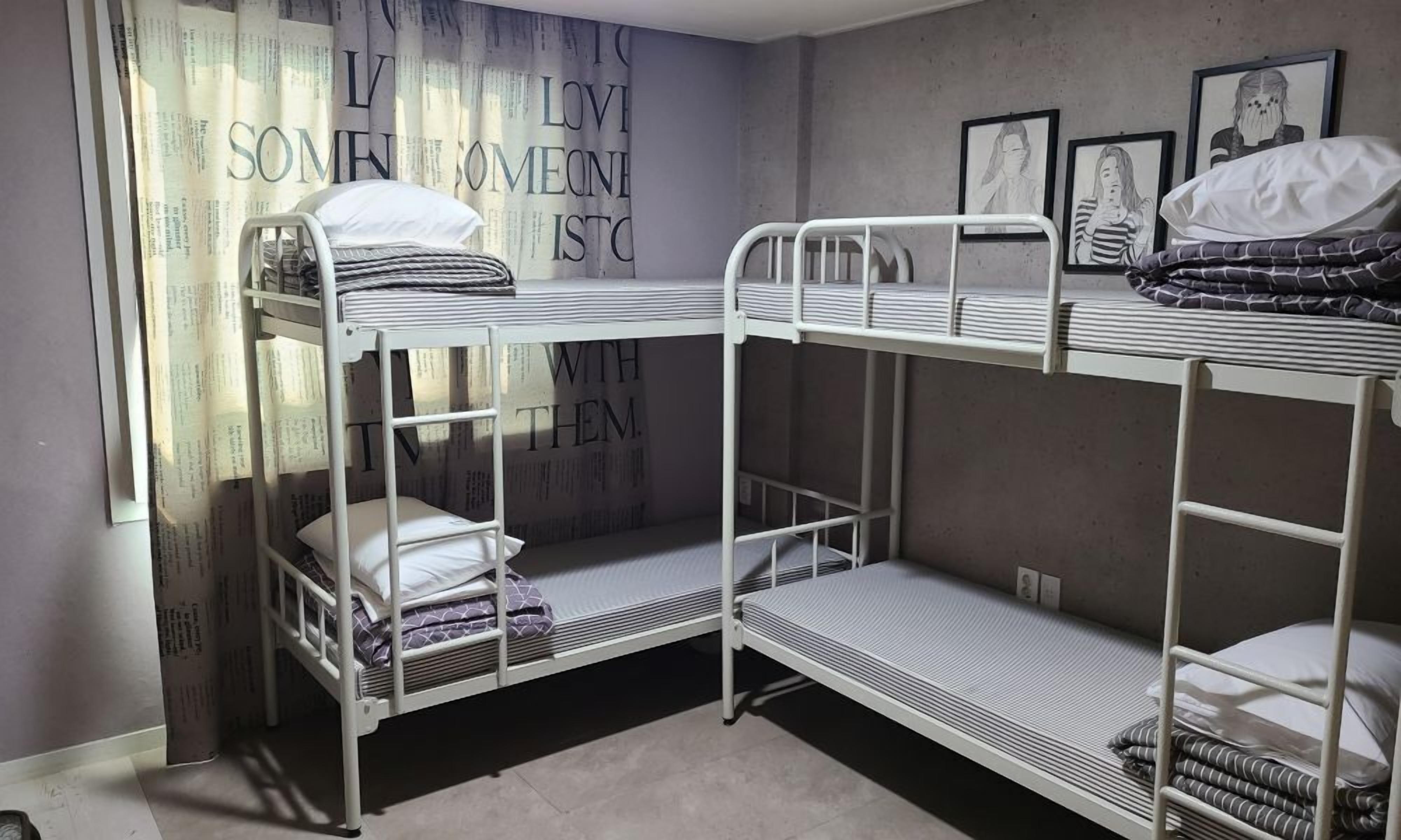 A bunk bed room with a window, a poster on the wall, and framed artwork.