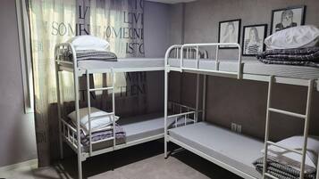 A bunk bed room with a window, a poster on the wall, and framed artwork.
