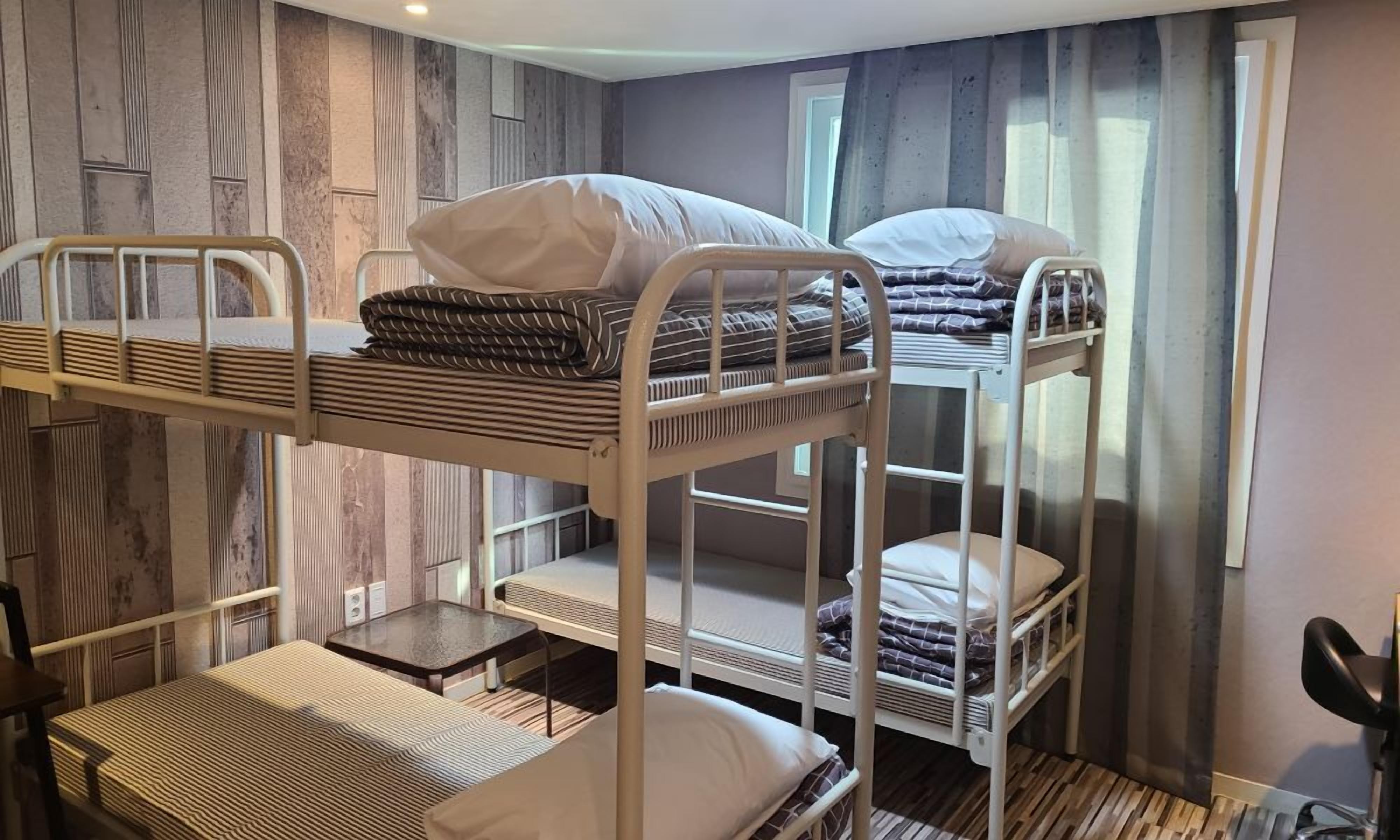 A bunk bed room with a wooden wall and a window with curtains.