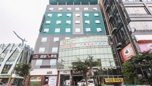 Un hôtel à plusieurs étages, doté d’une façade moderne, avec une enseigne bien visible indiquant « HÔTEL DEAN » au sommet.