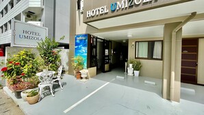 The exterior of Hotel Umizola with a clear entrance, potted plants, and a signboard. - Hotel Umizola (Naha)