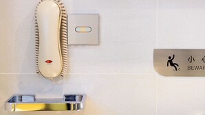 A bathroom with a hand dryer, a toilet paper holder, a soap dispenser, and a sign with a wheelchair symbol. - LAVANDE HOTEL GZ ZHENGJIA PLAZA BRANCH (Guangzhou)