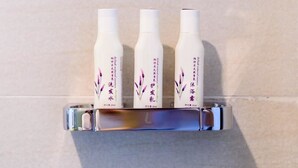 A bathroom with a white towel dispenser and three bottles of lotion on a shelf. - LAVANDE HOTEL GZ ZHENGJIA PLAZA BRANCH (Guangzhou)