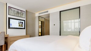 A hotel room with a large bed, a desk with a chair, a TV mounted on the wall, and a sliding door leading to a bathroom. - LAVANDE HOTEL GZ ZHENGJIA PLAZA BRANCH (Guangzhou)