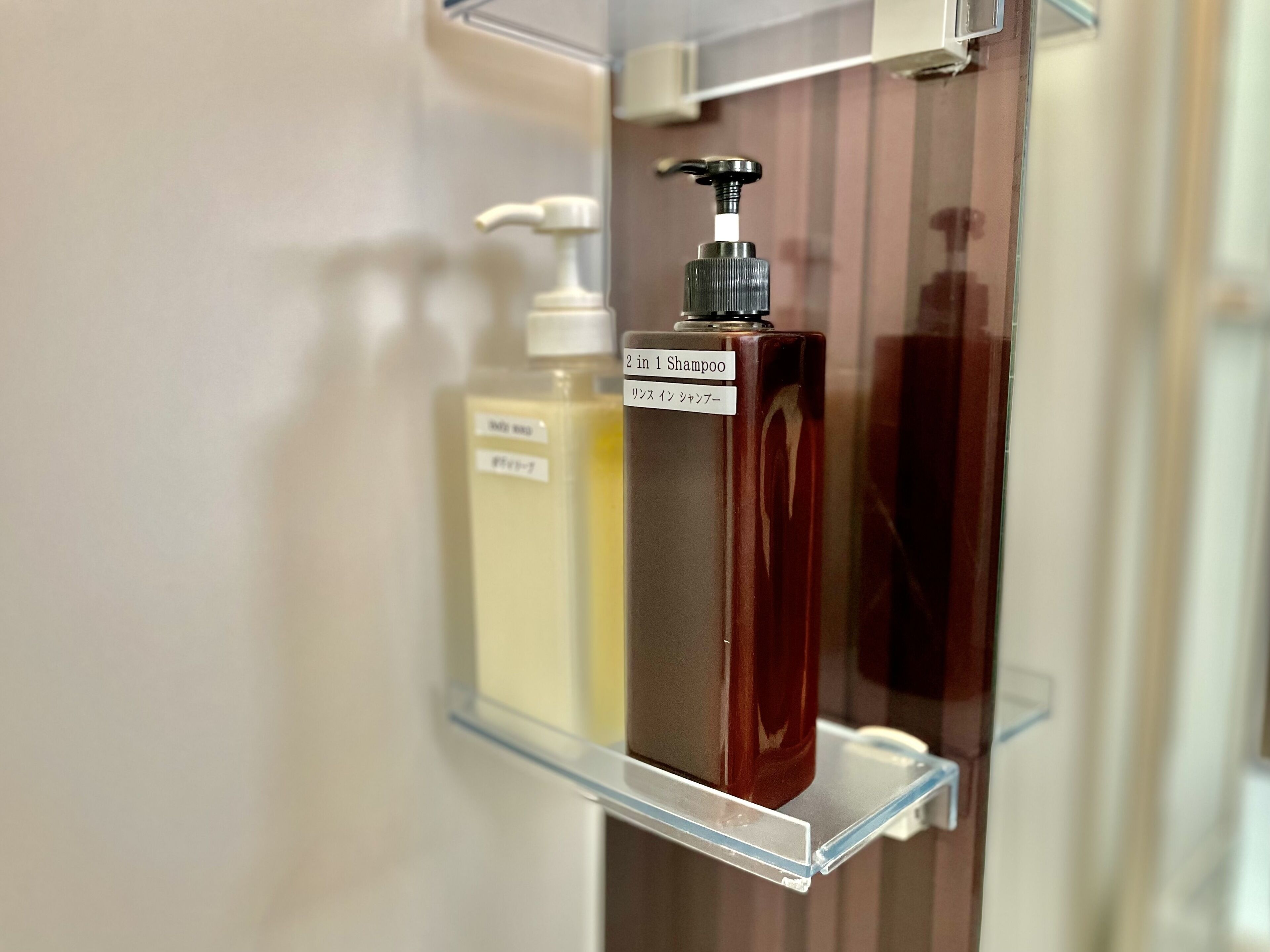 Un baño con un estante despejado que sostiene una botella de champú y una de loción.