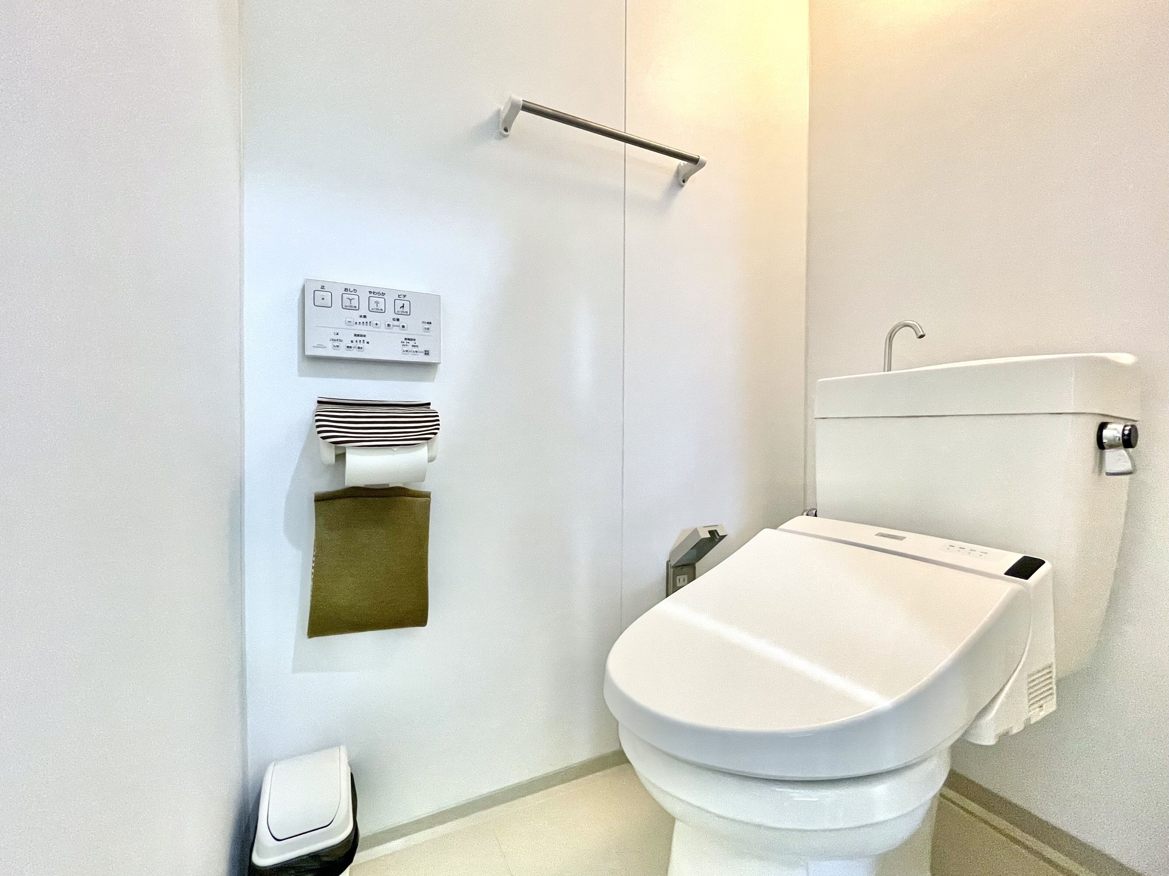 A modern bathroom with a toilet, a hand dryer, and a paper towel dispenser.