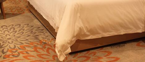 Una habitación de hotel con una cama grande, una silla y una alfombra estampada.
