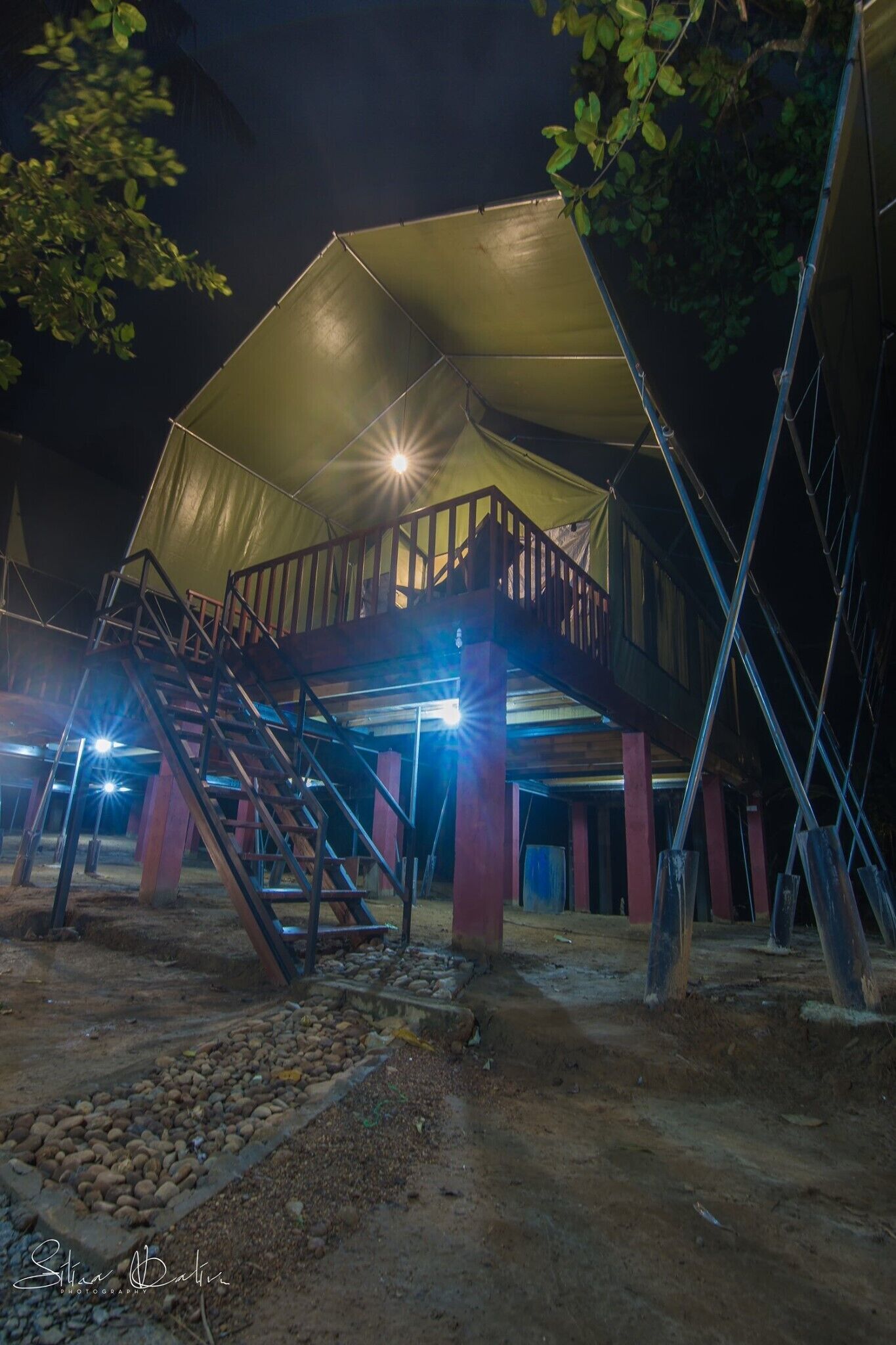 Una gran estructura tipo tienda de varios niveles con una escalera de madera que conduce a una cubierta superior.