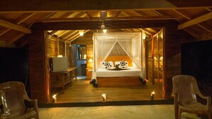 A cozy room with a bed under a canopy, a desk with a lamp, and two chairs. - 360 Rainforest (Deniyaya)