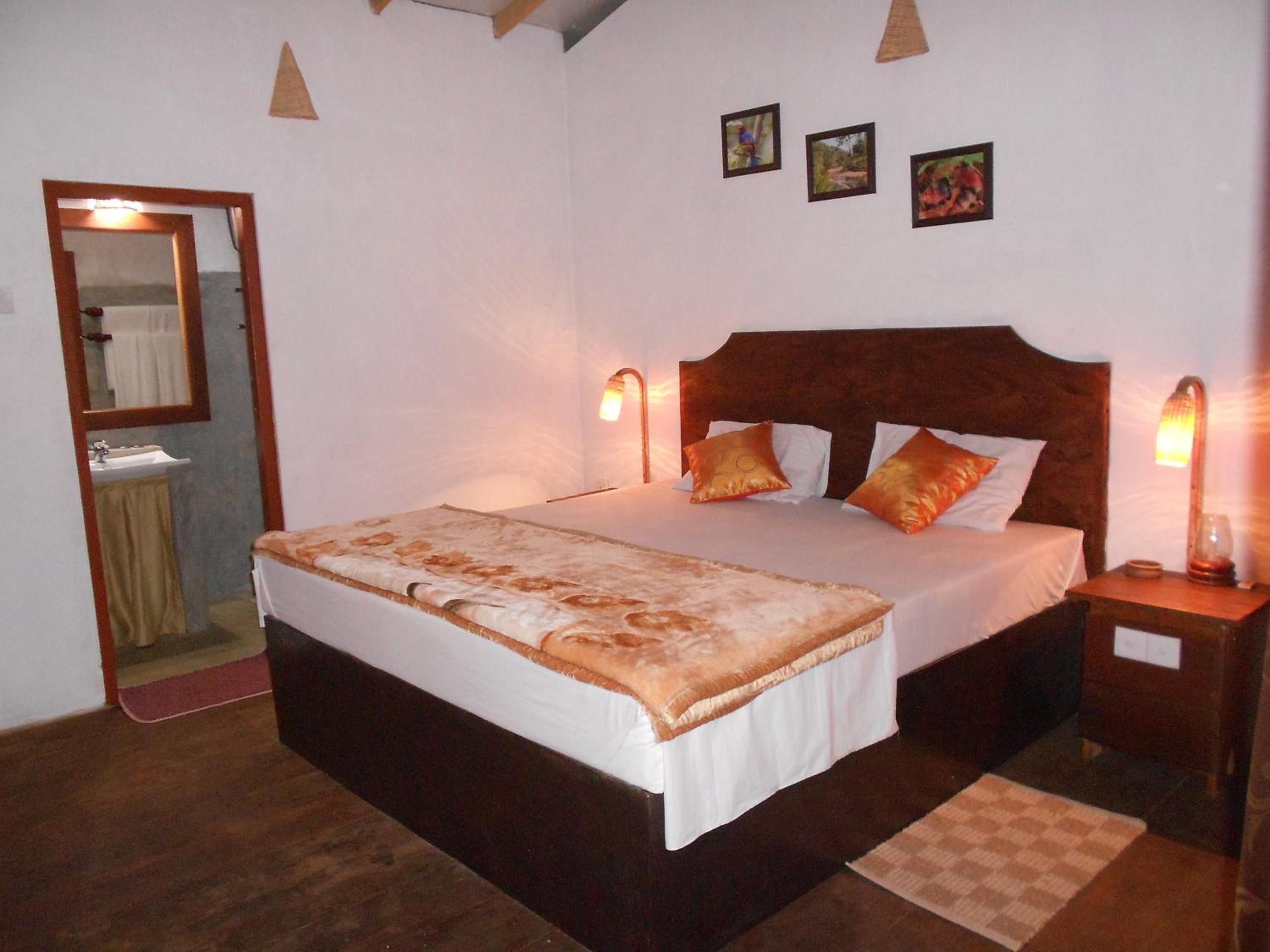 Een slaapkamer met een groot bed, twee nachtkastjes, een spiegel en drie ingelijste foto's aan de wand.