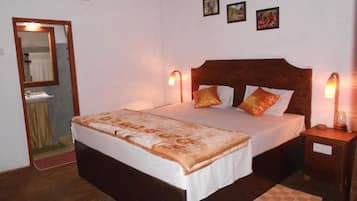 Een slaapkamer met een groot bed, twee nachtkastjes, een spiegel en drie ingelijste foto's aan de wand.
