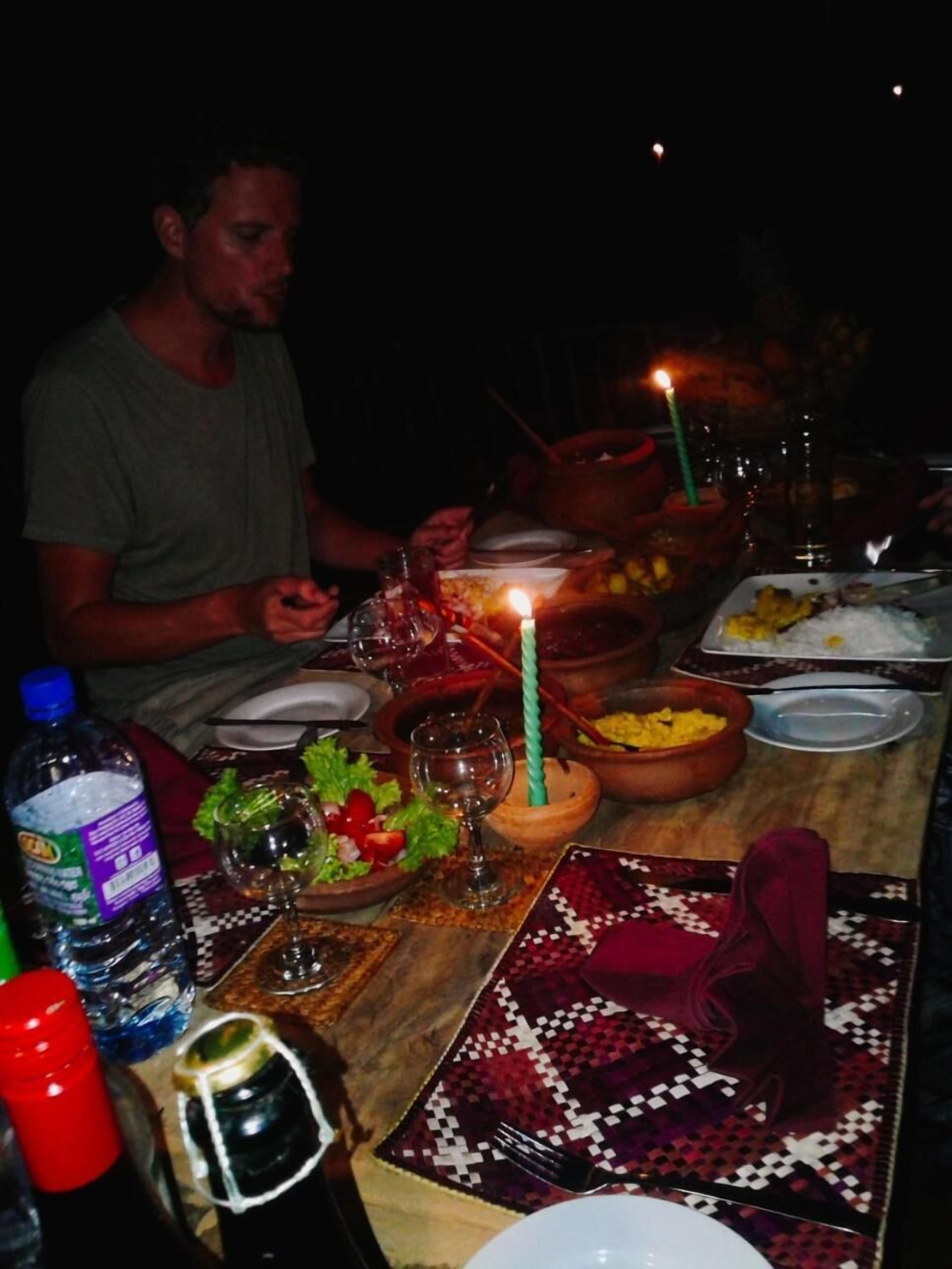 A dining table set for a meal with various dishes, a candle, and a bottle of water.