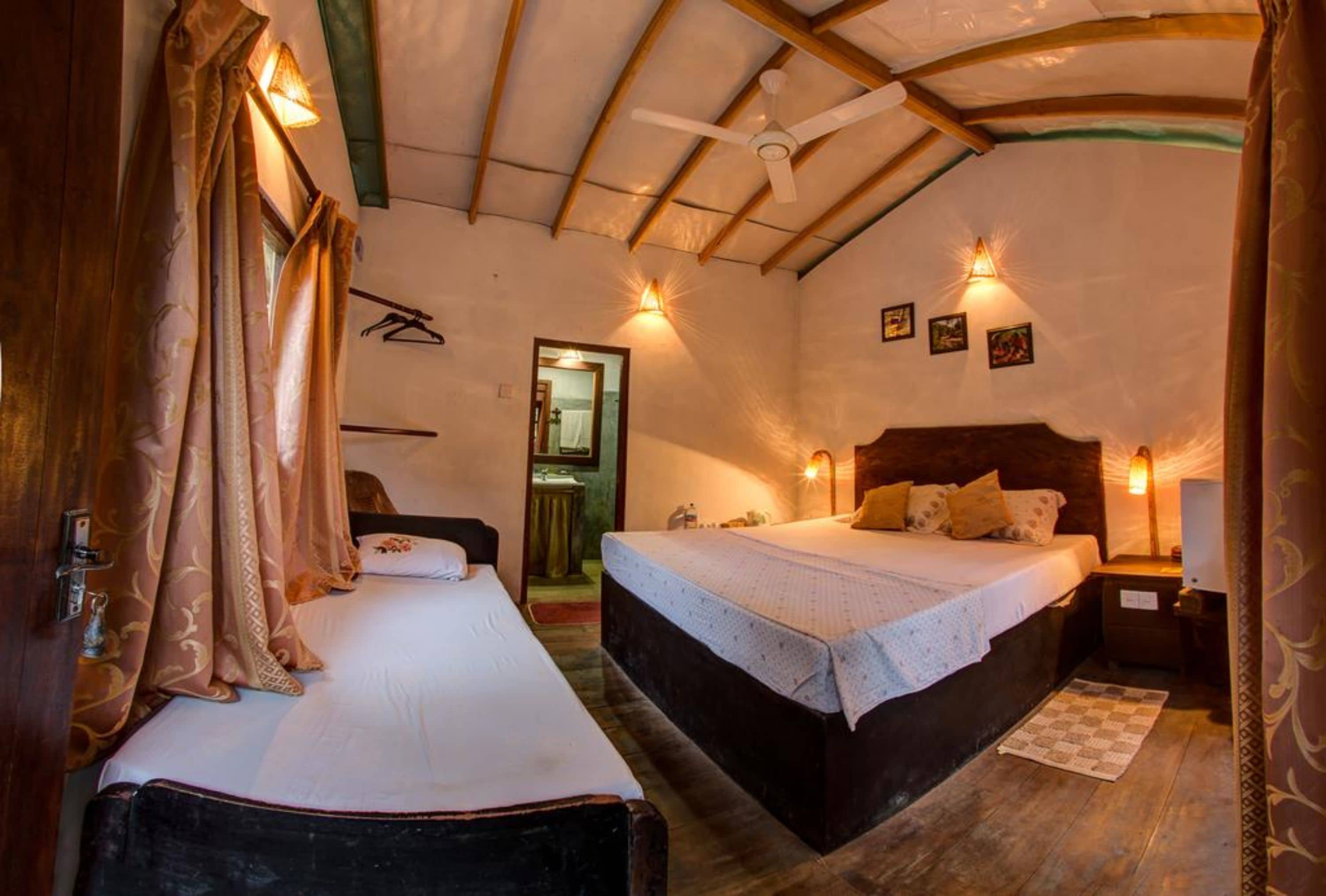 A cozy bedroom with two beds, a ceiling fan, and wall-mounted lights.