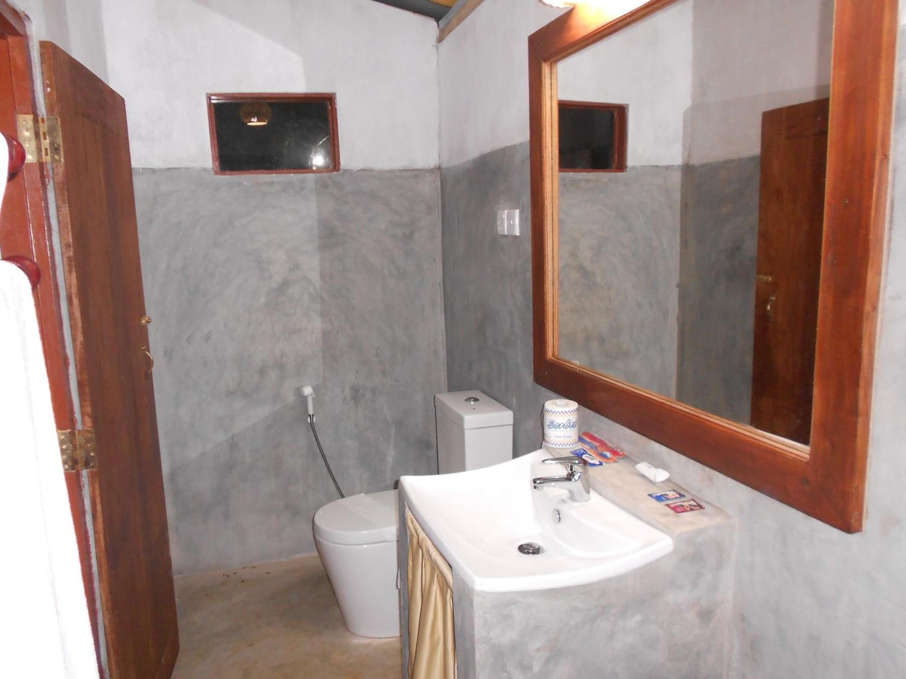 A bathroom with a white sink, a mirror, and a toilet.