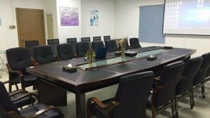 A conference room with a long table, black chairs, a projector screen, and posters on the walls. - Lavande Hotel (Guangzhou)