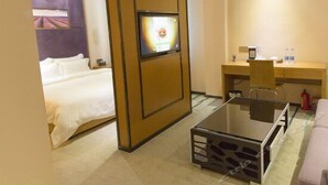A hotel room with a bed, a desk, a TV, and a glass coffee table. - Lavande Hotel (Guangzhou)