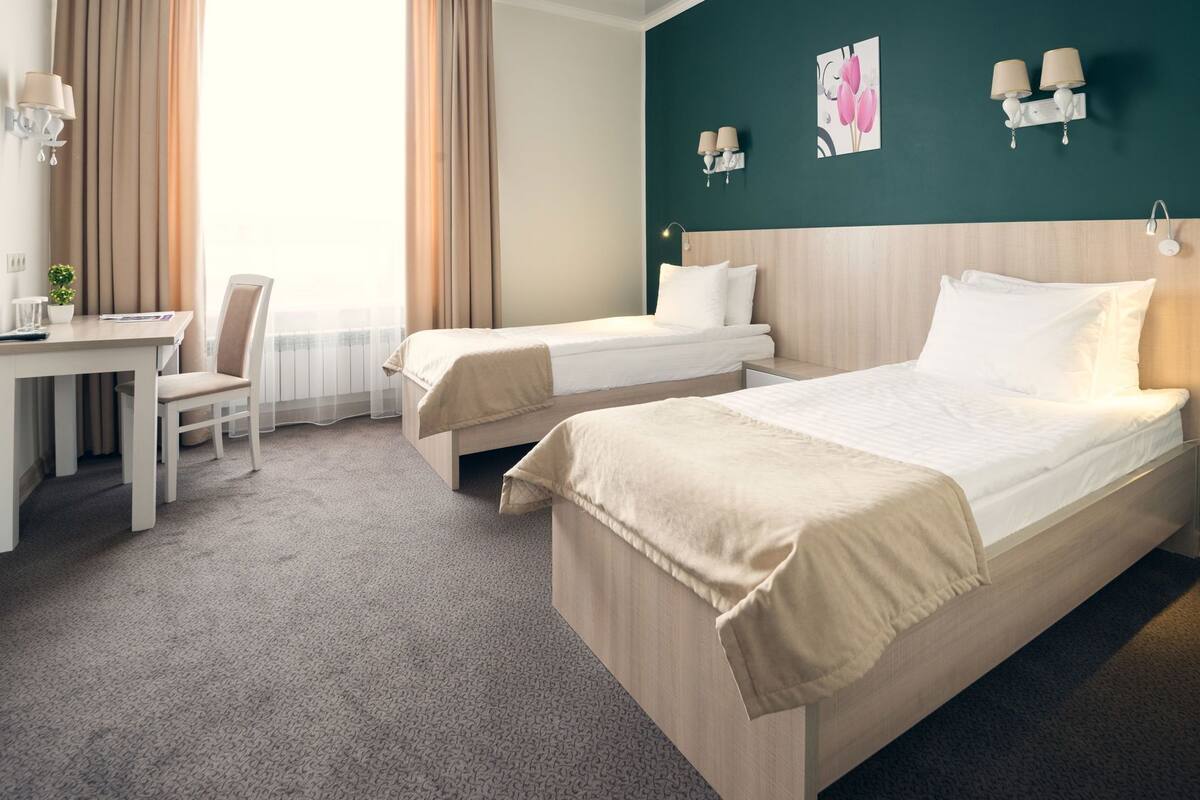 Una habitación de hotel con dos camas, un escritorio, una silla y vistas al exterior.