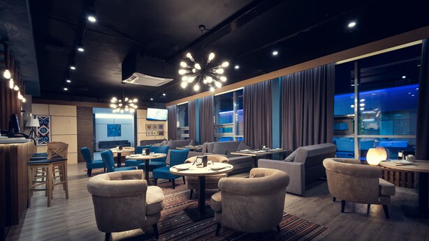 A modern lounge area with sofas, armchairs, and a bar. - AyKun Hotel (Astana)
