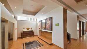 Um hall moderno com piso de madeira, balcão de recepção e obras de arte emolduradas na parede.