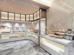 En modern frukostbuffé med olika matstationer och ett golv av marmor.