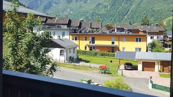 Ein Balkon mit Blick auf ein Wohngebiet, Häuser und schneebedeckte Berge im Hintergrund.
