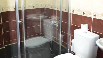 A bathroom with a glass-enclosed shower, a white toilet, and a sink.