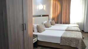 Une chambre d’hôtel avec deux lits, une table de chevet, une armoire et un luminaire fixé au mur.