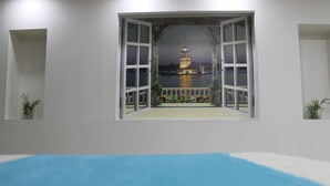 Une pièce dotée d’une grande fenêtre donnant sur un plan d’eau et sur une tour.