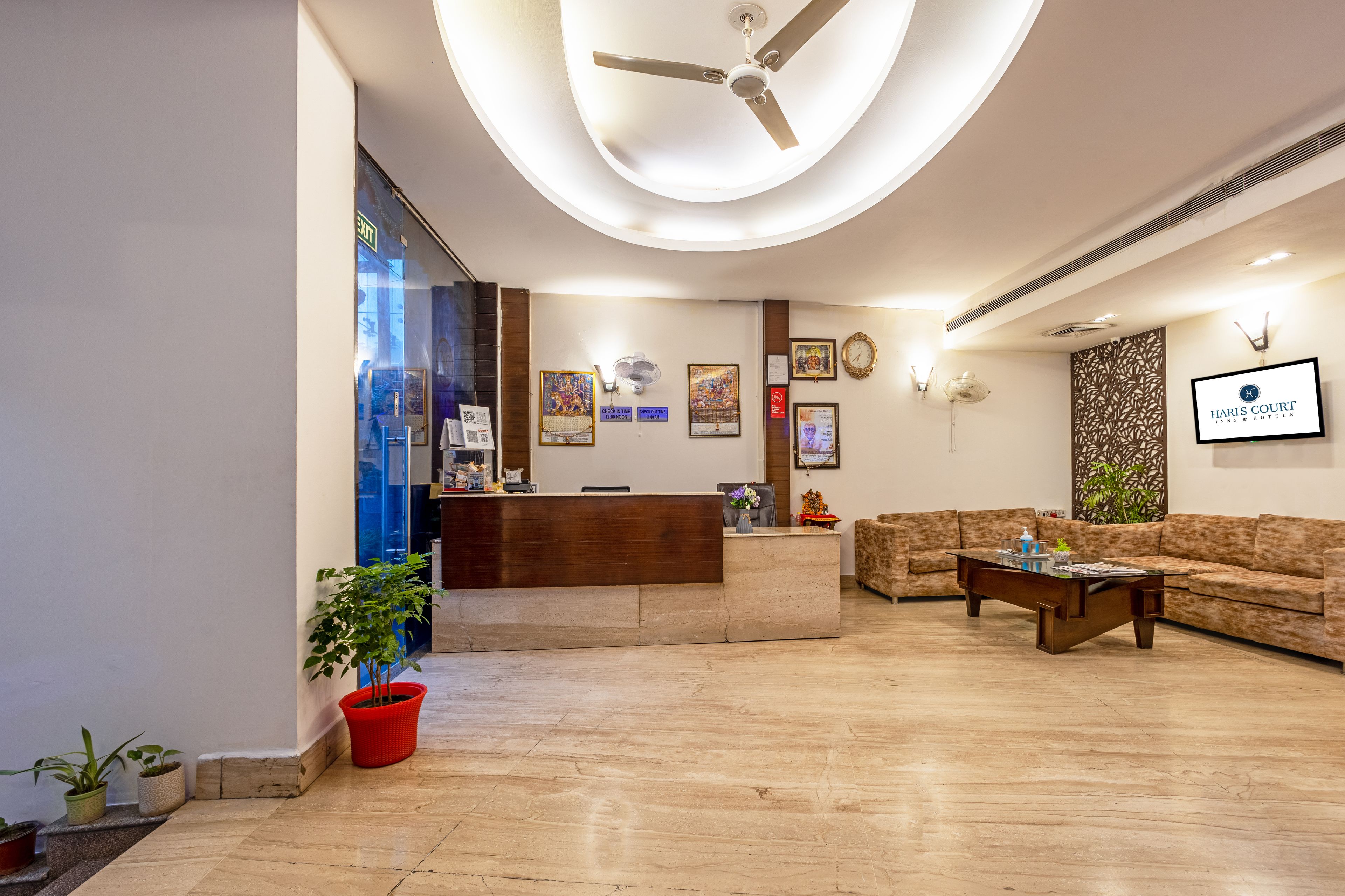A hotel reception area with a reception desk, a sofa, and a ceiling fan.