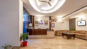 Ein Hotel-Empfangsbereich mit einer Rezeption, einer Couch und einem Deckenventilator.