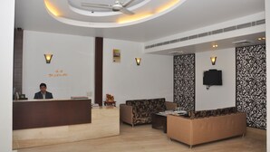 A reception area with a wooden reception desk, a sofa, and a patterned wall.