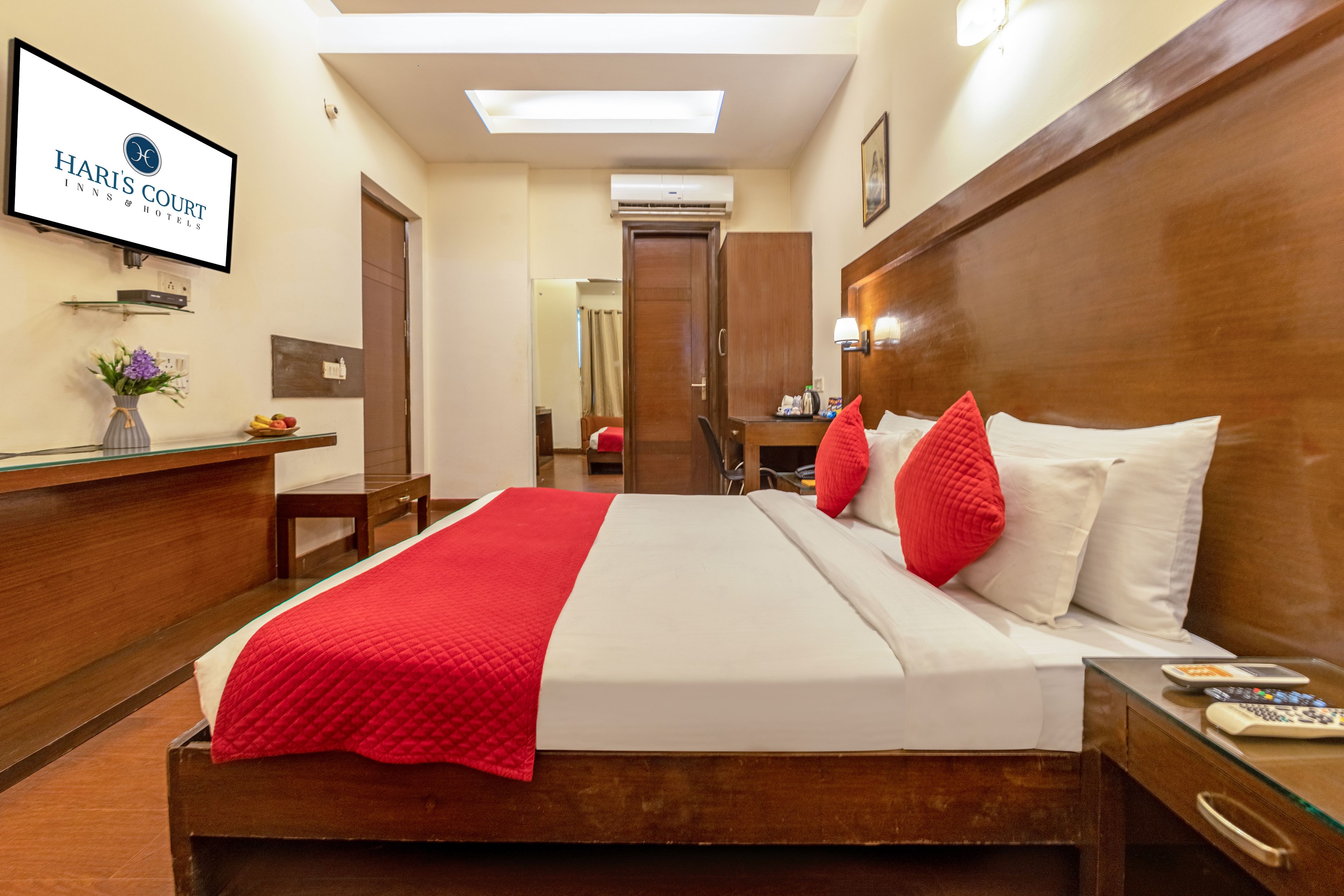 Une chambre d’hôtel avec un lit, une table de chevet et un bureau agrémenté d’un vase de fleurs.