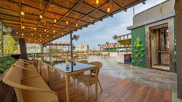 An outdoor seating area with wicker furniture, a glass table, and a view of the cityscape.