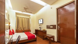 Ein Hotelzimmer mit Bett, Schreibtisch, Stuhl und Fernseher an der Wand.